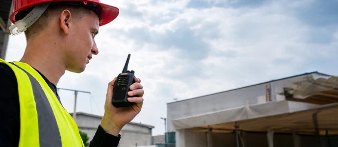 Ouvrier de chantier utilisant un talkie-walkie pour coordination sur site BTP